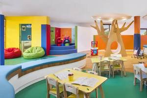 Kinderbereich im Hilton Ras Al Khaimah Beach Resort mit bunten Farben, Tischen, Stühlen und Spielzeug.