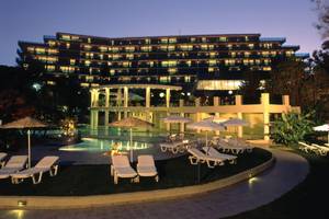 Abendliche Ansicht des Calypso Beach Hotels mit illuminierten Fenstern und Außenbereich mit Pool und Liegestühlen.