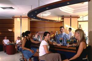 Gäste sitzen an der Bar des Calypso Beach Hotels und unterhalten sich mit dem Barkeeper.