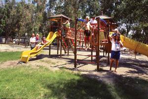 Familie genießt einen Tag auf dem Spielplatz im Freien, mit Rutschen und Klettergerüsten
