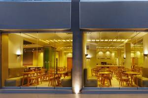 Außenansicht des Anna's House Restaurants mit großen Glasfenstern und innenliegenden Holztischen und Stühlen.