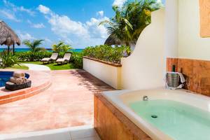 Außenbereich des El Dorado Royale Spa Resorts mit Whirlpool, Lounge-Sesseln und Blick auf den Ozean.