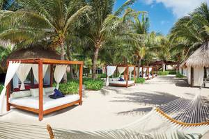 Strandbetten im El Dorado Royale Spa Resort mit weißen Vorhängen und blauen Handtüchern.
