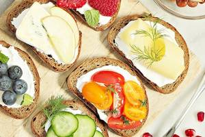 Frühstücksplatte mit Obst, Gemüse und Aufstrich auf einem Holzbrett