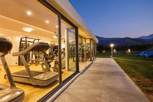 Außenansicht des Fitnessraums von Annas Haus mit Trainingsgeräten und Panoramablick auf die Berge