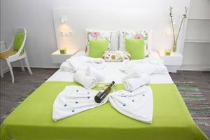 Zimmer im Alexander House mit grünem Bett und frischen Handtüchern.