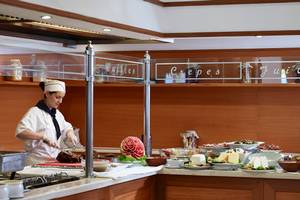 Buffettisch im Serita Beach Hotel mit verschiedenen Gerichten und einer Frau, die serviert.