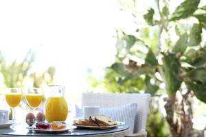 Frühstückstisch im Freien mit Orangensaft, Eiern und Brötchen im Serita Beach Hotel.