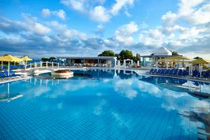 Außenpool des Serita Beach Hotels mit Lounge-Stühlen und gelben Sonnenschirmen