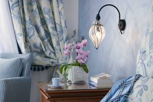 Serita Beach Hotel Zimmer mit Nachttisch, Orchideen, Bücher und Wandlampe.