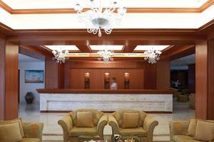Hotellobby des Serita Beach mit goldenen Möbeln, Kronleuchtern und einem Empfangstresen.
