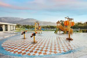 Annas House Spielplatz mit Wasserspielanlage und Bergpanorama im Hintergrund.