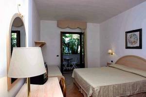 Gabbiano Beach Vieste Hotelzimmer mit Bett, Tisch, Stühlen und Spiegel.