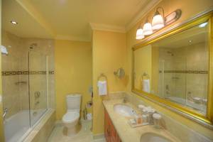 Badezimmer im Radisson Blu Resort & Spa, Malta Golden Sands mit gelben Wänden, einer Badewanne und einer Dusche.