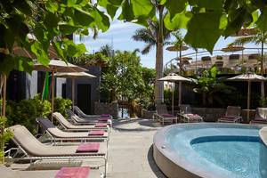 Pool-Lounge-Bereich im Garten des Bohemia Suites & Spa mit Liegestühlen und Sonnenschirmen.
