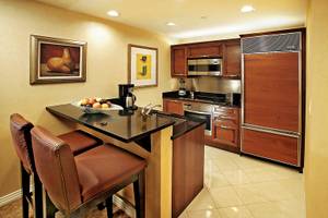 Küche im The Signature At MGM Grand Suite mit Holzschränken und schwarzem Arbeitsbereich.
