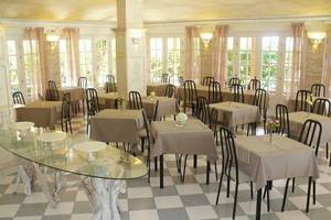 Innenansicht des Restaurants des Nefeli Hotels mit gedeckten Tischen und Stühlen auf einem gemusterten Boden.