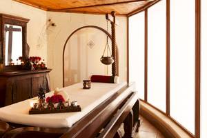 Spa-Behandlungsraum im Kempinski Hotel San Lawrenz Malta mit einem Massagetisch, Kerzen und einem Spiegel.
