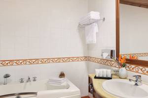 Badezimmer im Kempinski Hotel San Lawrenz Malta mit Badewanne, Waschbecken, Spiegel und Dekoration.