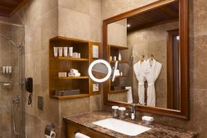 Badezimmer im Kempinski Hotel San Lawrenz Malta mit Regendusche, Spiegel und Waschbecken.