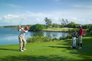 Golfer spielt am Wasser im Constance Belle Mare Plage Hotel.