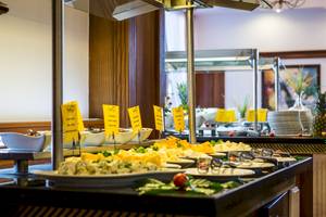 Buffet-Tisch im Helena Sands Hotel mit verschiedenen Käsesorten und anderen Gerichten.
