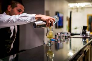 Ein Barkeeper mischt einen Cocktail in einem Glas im Helena Sands Hotel.