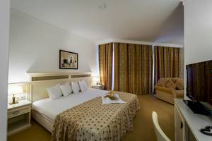 Helena Sands Hotelzimmer mit Bett, Couch, Fernseher und Frühstückstablett
