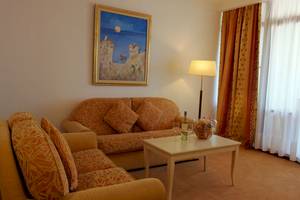 Wohnbereich des Helena Sands Hotels mit Sofas, Tisch, Lampe und Gemälde an der Wand.