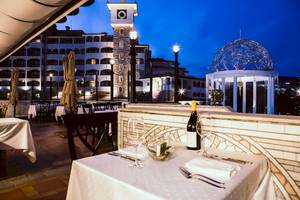 Abendessen auf der Terrasse des Helena Sands Hotels mit Tisch, Wein und Aussicht auf das Gebäude.