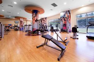 Fitnessbereich im Sueno Hotels Beach Side mit diversen Trainingsgeräten und großen Fenstern.