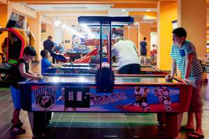 Spielhalle im Sueno Hotels Beach Side mit Kindern, die an einem Hockey-Arcade-Spiel teilnehmen.
