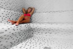 Eine Frau liegt in einer Sauna des Sueno Hotels Beach Side.