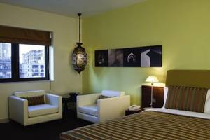 Zimmer im Manzil Downtown by Vida Hotel, Dubai mit zwei Sesseln, einem Bett und einer Lampe.
