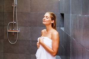 Eine Frau genießt eine Dusche im Badezimmer des Meeru Island Resort & Spa.