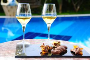 Zwei Gläser Weißwein neben einer Schokoladentafel am Pool des Delphin BE Grand Resort.