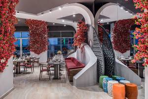 Elegantes Restaurant im Delphin BE Grand Resort, dekoriert mit leuchtend roten Blumen und stilvollen Möbeln.