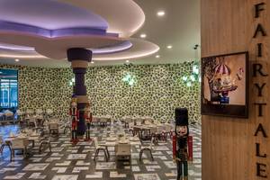 Gemütliches Restaurant im Delphin BE Grand Resort mit buntem Dekor und festlich gedeckten Tischen.