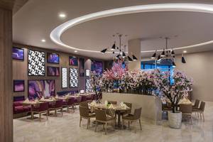 Elegantes Restaurant im Delphin BE Grand Resort mit modernen Möbeln und blühenden Kirschbäumen.