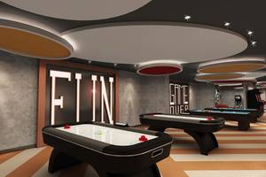 Moderne Spielelounge im Delphin BE Grand Resort mit Airhockey-Tischen und bunten Deckenlichtern.