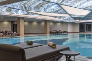 Innenansicht des Delphin BE Grand Resort mit einem Pool und luxuriösen Liegen.