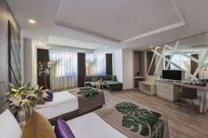 Moderne Zimmer im Delphin BE Grand Resort mit Doppelbetten, Fernseher und Wohnbereich.