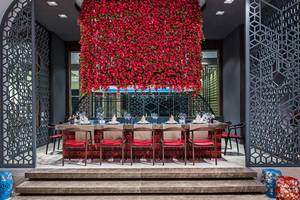 Ein eleganter Essbereich im Delphin BE Grand Resort mit einem Tisch voller Gläser und Tellern, umgeben von roten Blumen.