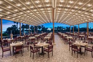 Geräumiges Restaurant des Delphin BE Grand Resort mit eleganten Tischen und schöner Beleuchtung im Freien.