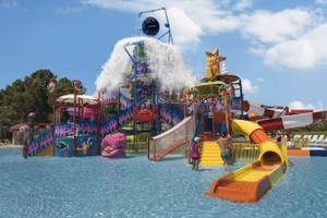 Wasserrutschen und Spielbereich für Kinder im Delphin BE Grand Resort, umgeben von klarem Wasser und sonnigem Himmel.