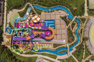 Aussicht auf die farbenfrohen Wasserrutschen des Delphin BE Grand Resort mit Schwimmbädern und Grünflächen.