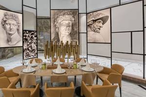 Elegantes Restaurant im Delphin BE Grand Resort mit stilvollen Stühlen und beeindruckenden Kunstwerken an der Wand.