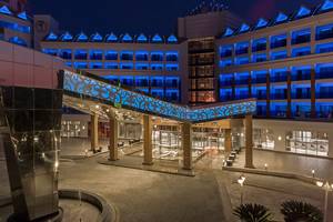 Eingangsbereich des Delphin BE Grand Resorts, beleuchtet mit blauem Licht und modernem Design bei Nacht.