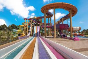 Mehrere bunte Wasserrutschen im Delphin BE Grand Resort bei blauem Himmel