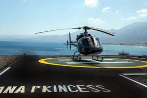 Ein schwarzer Hubschrauber der Nana Princess steht auf einem Landeplatz am Strand.